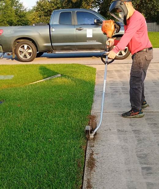 Cutting a crisp edge along a customer's driveway with the blade edger, crew truck behind